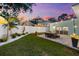 Spacious backyard with a stone patio, seating, landscape, and string lights under a colorful sunset at 475 Crystal Beach, Crystal Beach, FL 34681