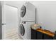 Modern laundry room featuring stacked washer and dryer with wood and metal shelving at 475 Crystal Beach, Crystal Beach, FL 34681