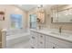 Modern bathroom featuring dual sinks, white cabinets, and a tiled tub with a clean, elegant design at 4915 Fort Peck Rd, New Port Richey, FL 34655
