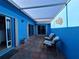 Outdoor patio featuring tiled flooring, seating, a retractable awning and a vibrant blue accent wall at 5404 Springwood Blvd # 5404, Pinellas Park, FL 33782