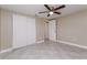 Bright bedroom features tile floors, neutral paint, ceiling fan, and closet with sliding doors at 7405 Oakshire Dr, Port Richey, FL 34668