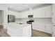 Modern kitchen featuring white cabinets, stainless steel appliances, a center island, and sleek countertops at 8514 Dove Bog Ter, Parrish, FL 34219