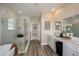 Bright bathroom with a glass-enclosed shower, a soaking tub, and stylish double vanity sinks at 10009 Surrey Rose Dr, San Antonio, FL 33576