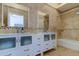 Bright bathroom with a double vanity, bathtub, travertine tile and matching mirrors at 1089 Virginia St, Dunedin, FL 34698