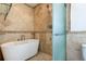 Elegant bathroom with tub, frosted glass shower, and neutral tile at 1089 Virginia St, Dunedin, FL 34698