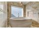 Luxurious round bathtub with a window view, framed by marble tile and modern lighting at 1089 Virginia St, Dunedin, FL 34698