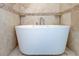 Freestanding bathtub with modern fixtures surrounded by neutral-toned tiles with decorative border and flooring at 1089 Virginia St, Dunedin, FL 34698