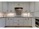 Spacious kitchen with a cooktop with range hood, decorative tile, stainless steel oven, and custom cabinets at 1089 Virginia St, Dunedin, FL 34698