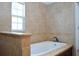 Relaxing soaking tub with tile surround and granite countertops at 11141 Rex Hunter Ln, Lithia, FL 33547