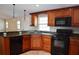 Kitchen featuring tile flooring, wooden cabinetry, granite countertops, and black appliances at 11141 Rex Hunter Ln, Lithia, FL 33547