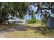 Exterior view of the home and shed surrounded by grass and mature trees at 11141 Rex Hunter Ln, Lithia, FL 33547
