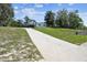 A single-story home sits atop a grassy hill, accessible via a long, cracked concrete driveway at 11409 Spring Hill Dr, Spring Hill, FL 34609