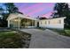 Charming home featuring a covered carport, screened porch, and a beautiful sunset sky at 11409 Spring Hill Dr, Spring Hill, FL 34609