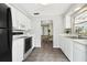 Kitchen boasts white cabinetry and appliances, tile floors, and view to dining area at 11409 Spring Hill Dr, Spring Hill, FL 34609