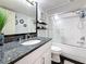 Granite countertop bathroom vanity featuring a tub and shower with a glass door and decorative accessories at 120 1St E St # 104, St Petersburg, FL 33715