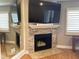 Elegant fireplace featuring a stone surround, hardwood floors, a mounted TV, and plantation shutters at 120 1St E St # 104, St Petersburg, FL 33715