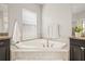 Relaxing bathroom with a corner soaking tub, dark cabinets, and a window at 3212 Calvano Dr, Land O Lakes, FL 34639