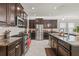 Contemporary kitchen with stainless steel appliances, granite countertops, dark wood cabinets, and large tile floors at 3212 Calvano Dr, Land O Lakes, FL 34639