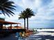 Scenic beachfront view featuring colorful chairs, palm trees, and a vibrant outdoor restaurant under a bright sky at 3643 Arbor Chase Dr, Palm Harbor, FL 34683