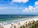 Beautiful beach view showcasing white sand, turquoise water, palm trees, and a lively pier scene at 3643 Arbor Chase Dr, Palm Harbor, FL 34683
