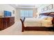 Comfortable main bedroom with a large window, dresser, tray ceiling, and plush carpeting at 3643 Arbor Chase Dr, Palm Harbor, FL 34683