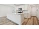 Modern kitchen featuring white cabinets, stainless steel appliances, an island, and wood-look flooring at 4210 Goldfoil Rd, Spring Hill, FL 34609