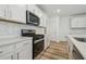 Well-lit kitchen with stainless steel appliances, white cabinetry, and a hexagon tile backsplash at 4210 Goldfoil Rd, Spring Hill, FL 34609