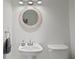 Clean bathroom with a pedestal sink, round mirror, updated fixtures, and toilet at 444 W Davis Blvd, Tampa, FL 33606