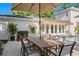 Outdoor patio space with a dining table under a large umbrella, surrounded by lush plants and a swimming pool at 444 W Davis Blvd, Tampa, FL 33606