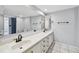 Bright bathroom featuring double sinks, a vanity with storage, a large mirror and a blue-tiled shower at 706 1St Ct, Palm Harbor, FL 34684