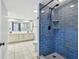 Modern bathroom featuring a blue tiled shower, safety bars, and a double sink vanity with marble tile flooring at 706 1St Ct, Palm Harbor, FL 34684
