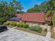 Condo with terracotta tiled roof and a screened-in porch, nestled amidst trees and landscaping at 706 1St Ct, Palm Harbor, FL 34684