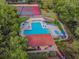 Aerial view of a community pool and tennis courts surrounded by mature landscaping at 706 1St Ct, Palm Harbor, FL 34684
