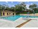 Community pool surrounded by trees, featuring lounge chairs for residents at 706 1St Ct, Palm Harbor, FL 34684