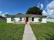Charming single-story home features a vibrant red door and stone accents, enhancing its curb appeal at 7102 Reindeer Rd, Tampa, FL 33619