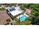 Aerial view showcasing a home with a sparkling pool and solar panels, nestled among mature trees at 7235 Sunshine S Dr, St Petersburg, FL 33705