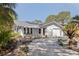 Charming home with a well-manicured front yard, featuring a circular driveway, lush landscaping, and a cozy front porch at 7235 Sunshine S Dr, St Petersburg, FL 33705