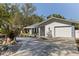 View of a charming home exterior showcasing a circular driveway, lush landscaping, and a cozy front porch with seating at 7235 Sunshine S Dr, St Petersburg, FL 33705