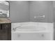 Soaking tub features white tile, neutral gray paint, granite vanity and chrome fixtures at 7246 Julian St, New Port Richey, FL 34653