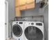 Laundry room featuring high-efficiency washer and dryer with wood cabinets and shelf for added storage at 7246 Julian St, New Port Richey, FL 34653