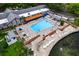 Community pool aerial view featuring comfortable lounge chairs, a hot tub, and scenic views overlooking the lake at 10820 Hachita Dr, Port Richey, FL 34668