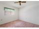 Bright bedroom with a ceiling fan, window with blinds, and neutral walls over pink carpet at 10820 Hachita Dr, Port Richey, FL 34668