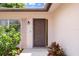 A welcoming front entrance with a decorative door, landscaped plants, and a charming exterior light fixture at 10820 Hachita Dr, Port Richey, FL 34668