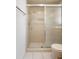 Tiled shower stall with sliding doors and a toilet, complemented by white tile flooring at 10820 Hachita Dr, Port Richey, FL 34668