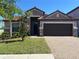 Attractive home boasting a red tile roof, lush lawn, and a paved driveway, complemented by tasteful stone accents at 12055 Cardinal Flower Dr, Riverview, FL 33579