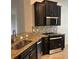 Well-equipped kitchen featuring dark wood cabinets, granite countertops, stainless steel appliances, and decorative backsplash at 12055 Cardinal Flower Dr, Riverview, FL 33579