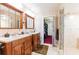 Bathroom boasting dual sinks with wooden cabinets, and a glass-enclosed shower, adjacent to the walk-in closet at 12311 Oakwood Dr, Hudson, FL 34669