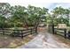 Long driveway lined by a black fence and leading up to a home surrounded by mature trees at 12311 Oakwood Dr, Hudson, FL 34669