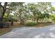 Landscaped front yard featuring a black fence, mature trees, and a glimpse of the home at 12311 Oakwood Dr, Hudson, FL 34669