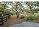Scenic property entrance framed by a black fence, mature trees, and lush greenery at 12311 Oakwood Dr, Hudson, FL 34669